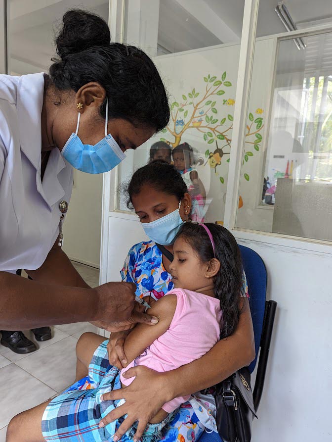 A Public Health Midwife administers a vaccine to a child at the Maternal and Child Clinic in Bokundara, Piliyandala. Credit: Aanya Wipulasena