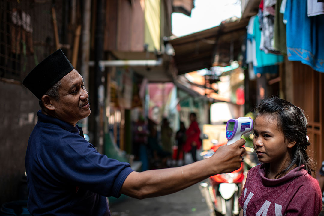 Sudirman, checks Zahara’s temperature during the COVID-19 outbreak in West Jakarta, Indonesia. Credit: UNICEF/2020/Arimacs Wilander