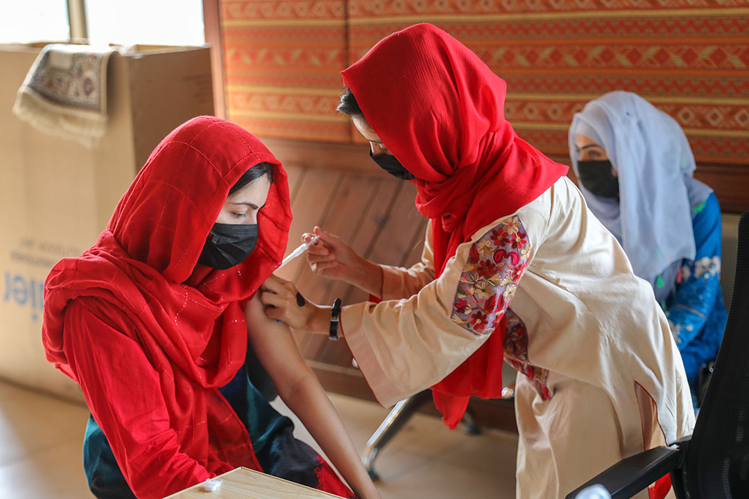 A health worker administers a COVID-19 vaccination to a young girl in a government vaccination centre in Islamabad. Credit: Gavi/2021/Asad Zaidi