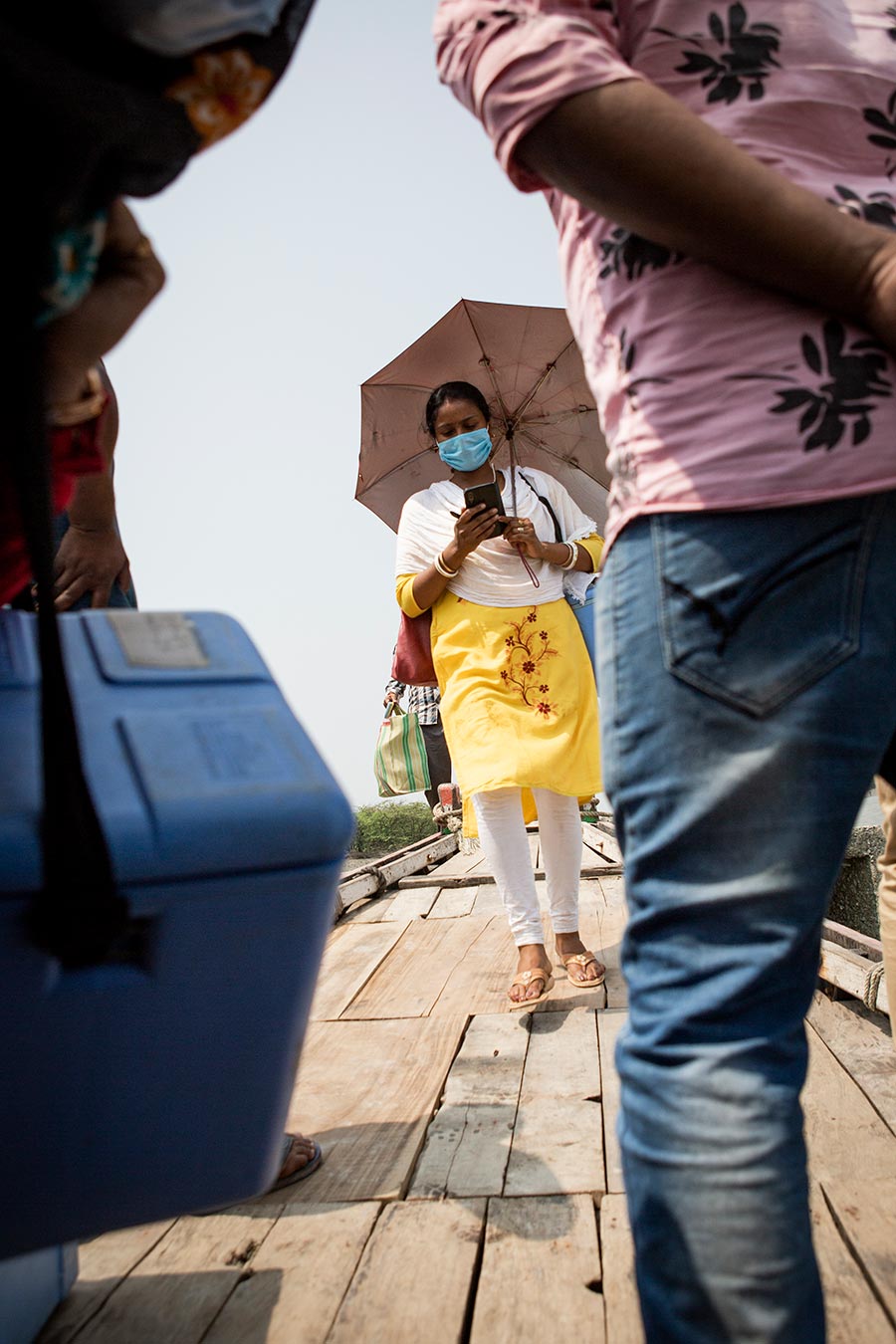 The floating healthcare workers transport vaccines in blue insulated carriers. Gavi/2022/Benedikt v.Loebell