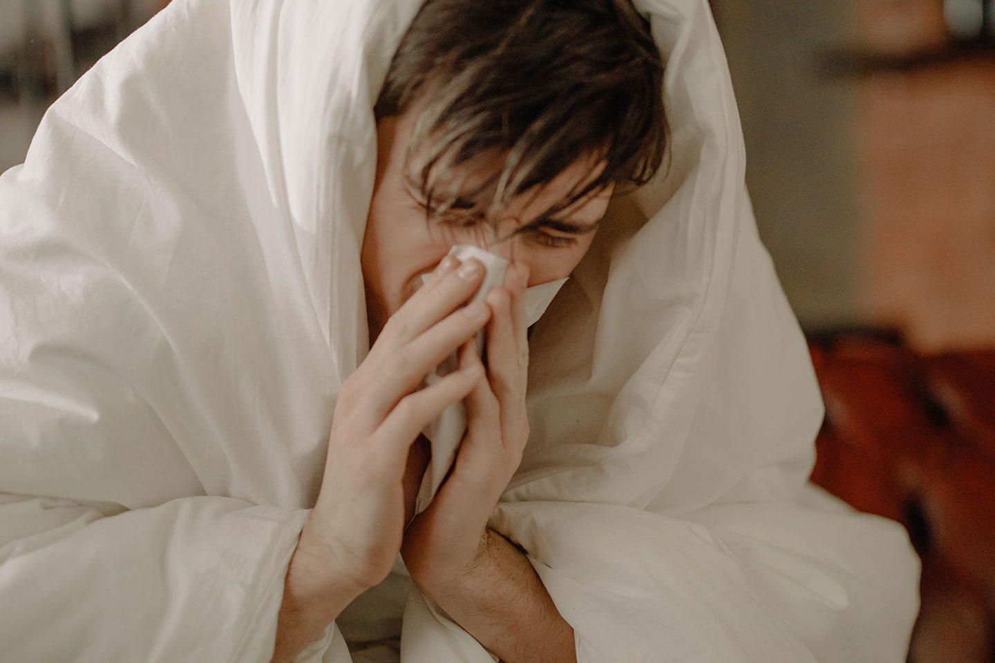 A sick man wiping his nose with tissue. Photo by cottonbro from Pexels