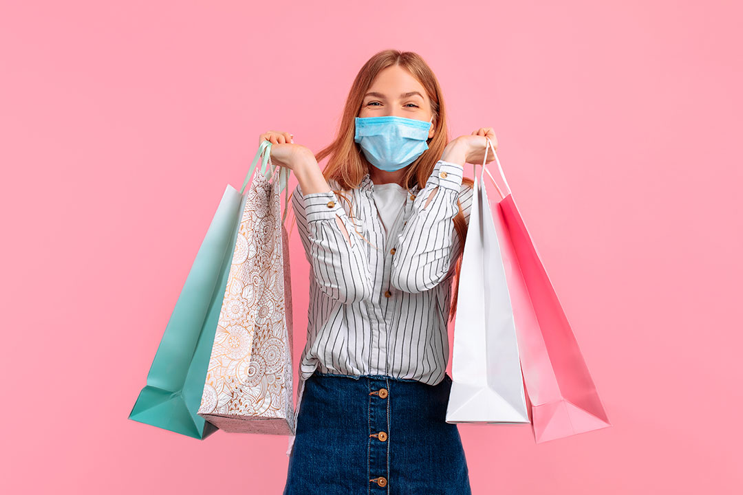 Excited young woman, holding up shopping bags of various colors.