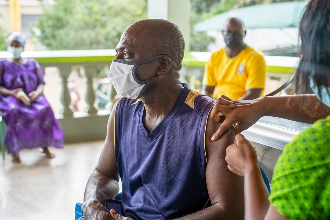An old African man receiving a vaccine injection from a healthcare provider
