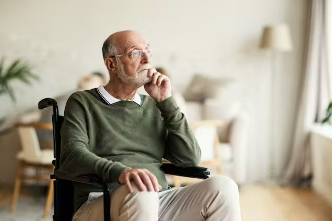 Old man sitting in a wheelchair looking out the window. Credit: Comeback Images/Shutterstock