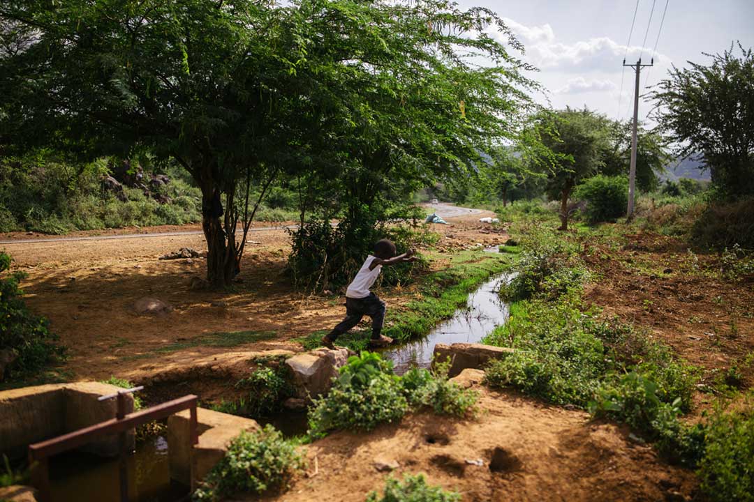 A boy leaps a rivulet in Baringo. Thorny mathenge trees dominate the landscape. Credit: Kang-Chun Cheng