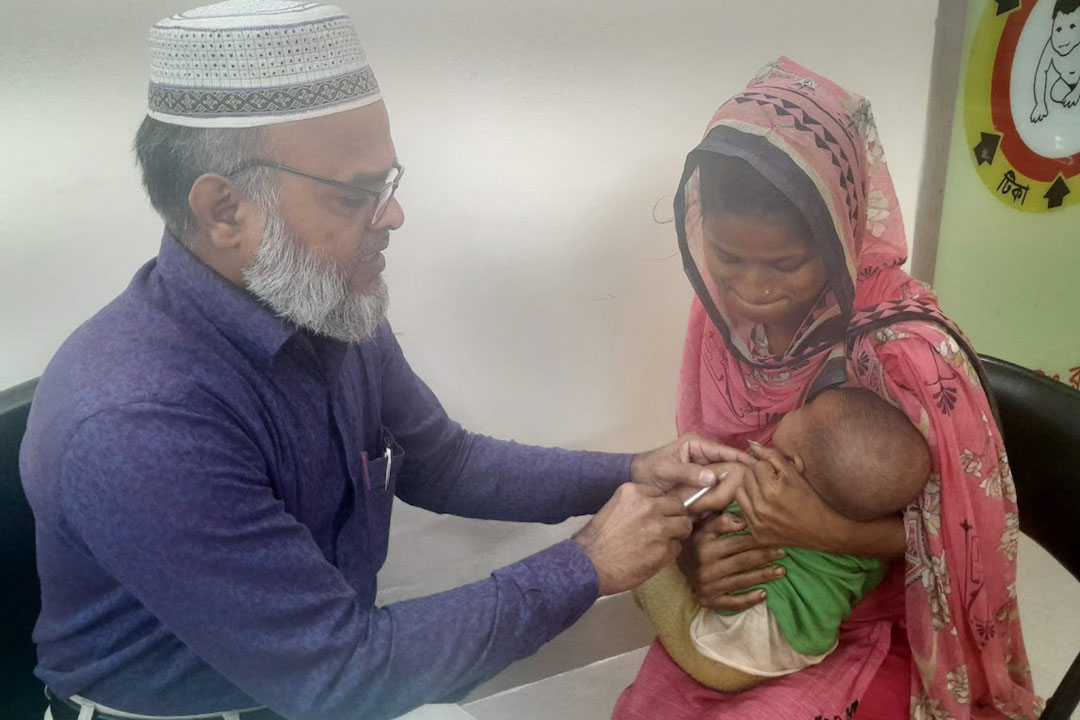 Medical Technologist Mujibar Rahman administering EPI vaccines to Tanha Akter, daughter of Aklima, at a vaccination centre at the EPI Headquarters in Mohakhali, Dhaka. Credit: Mohammad Al Amin