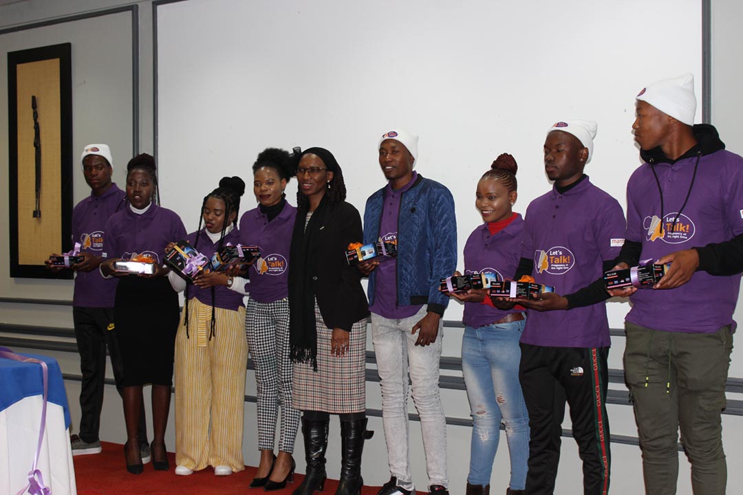 Peer Educators pose for a picture with UNESCO official Matsooana Sekokotoane with radios used to tune into to the Let's Talk! Radio drama in their villages. Credit Poloko Mokhele