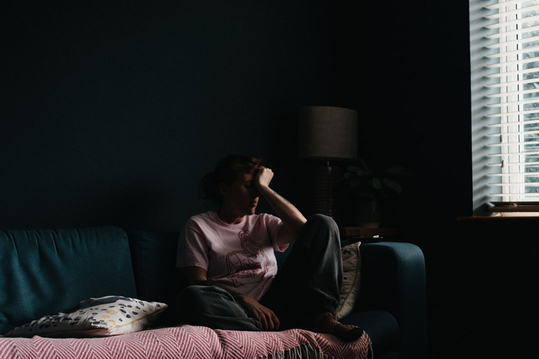 女人坐在黑暗的房间里，看起来很累。图片来源：安妮·斯普拉特 on Unsplash
