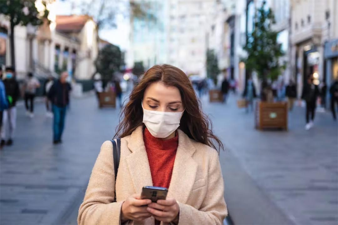 Woman walking on a street wearing a face mask. Credit: epic_images/Shutterstock