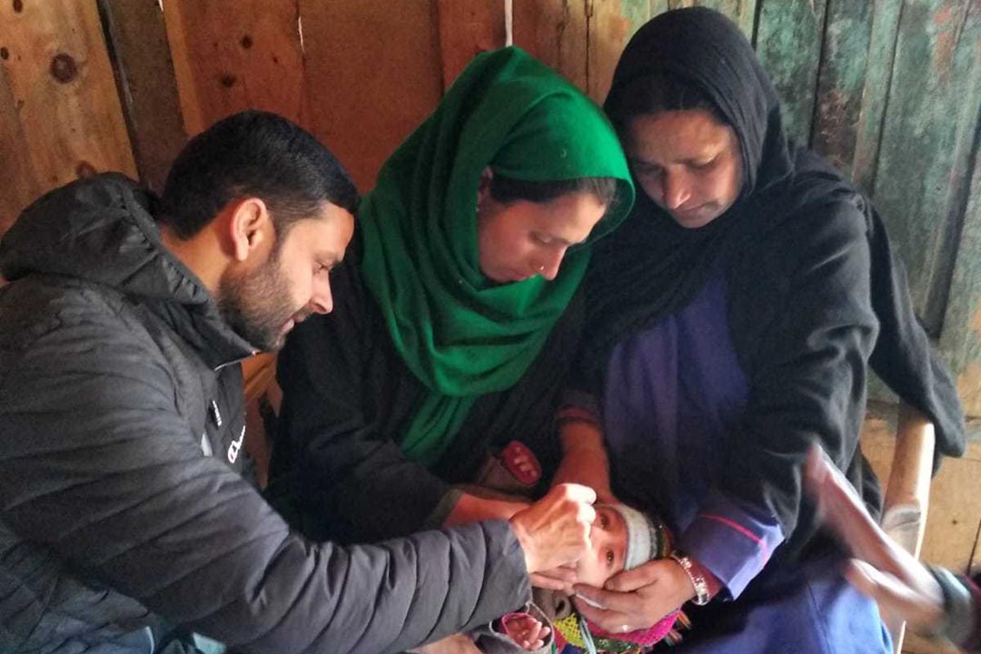 Irshad Ahmad gives an oral vaccine to an infant at Health Subcentre in Naga village. Credit: Nasir Yousufi