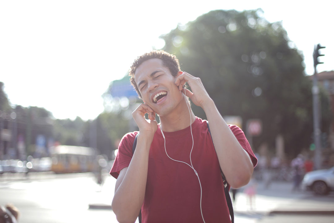 A man with headphones singing along and looking happy. Credit: Andrea Piacquadio on Pexels