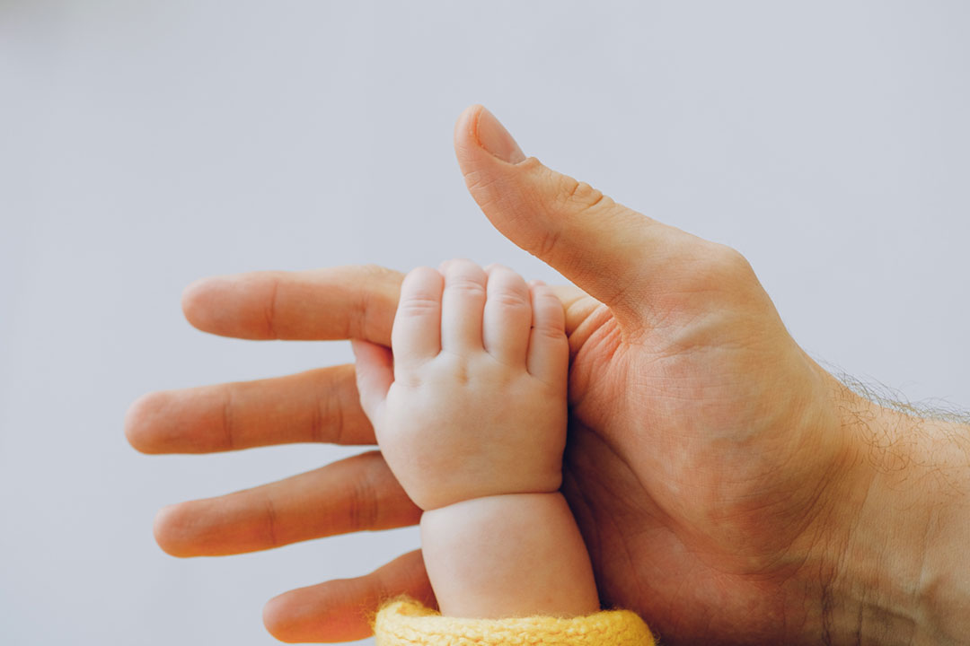 A baby hand holding on to the finger of an adult. Credit: Anna Shvets on Pexels