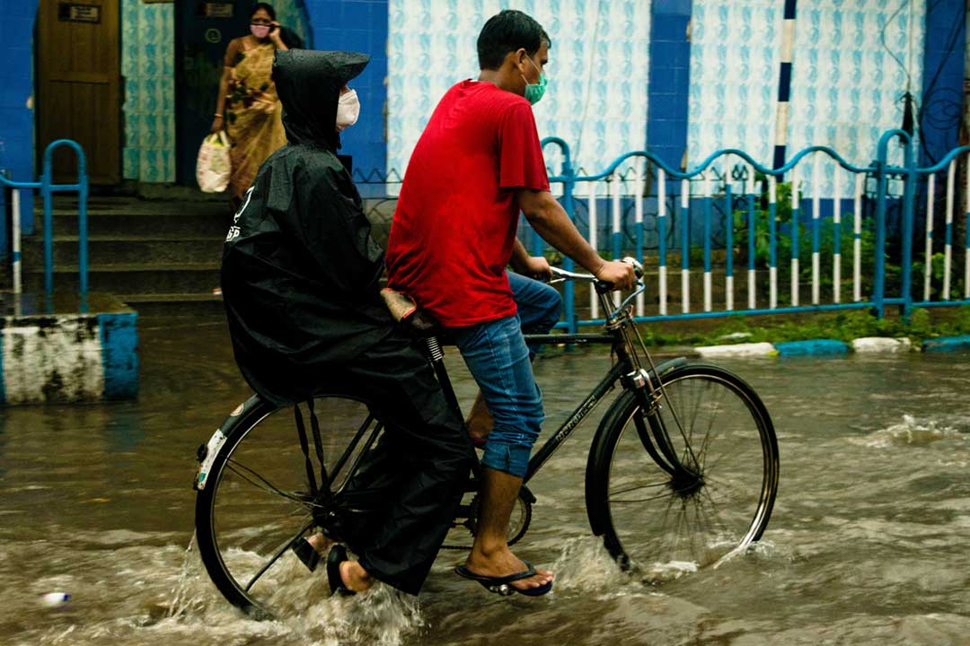 Two people riding a bike in a flooded city. Credit: Biplab Sau on Pexels