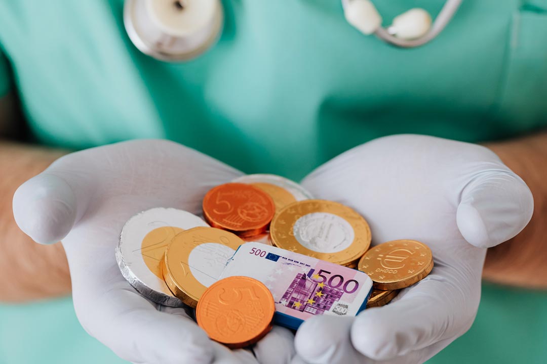 A medical worker holding toy money. Credit: Karolina Grabowska on Pexels