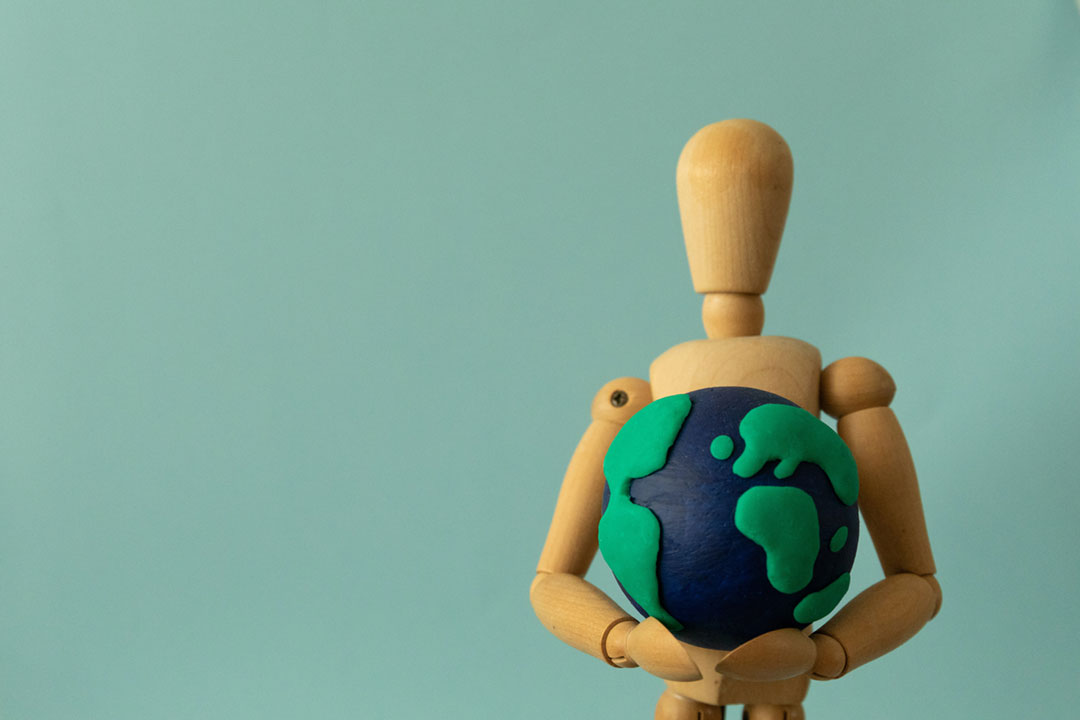 A figure holding a model of the earth. Credit: Mery Stockera on Pexels