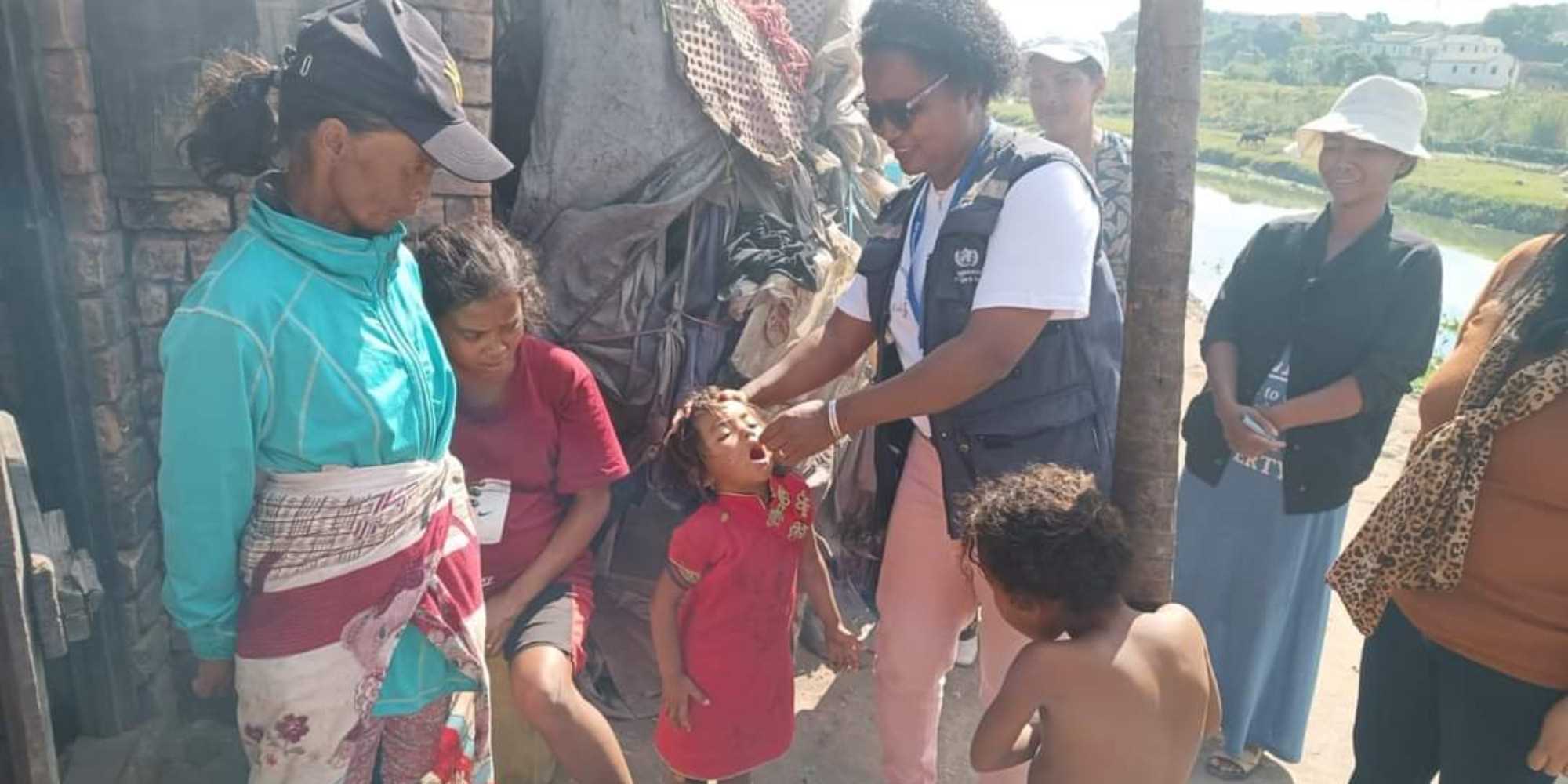 Un enfant reçoit son vaccin oral des mains d'un membre de l'équipe de l'OMS. Crédit : OMS