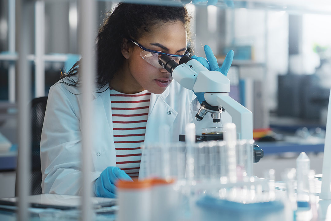 Portrait of a female scientist analysing test samples under a microscope.