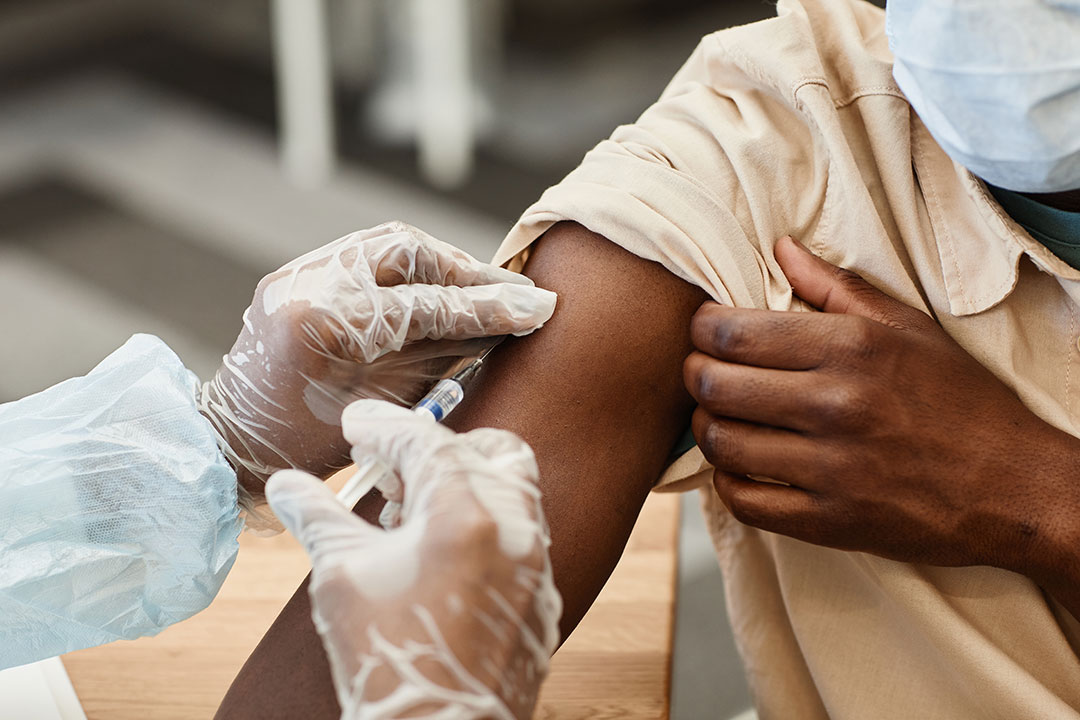 Close-up image of nurse in protective gloves giving patient injection of vaccine.