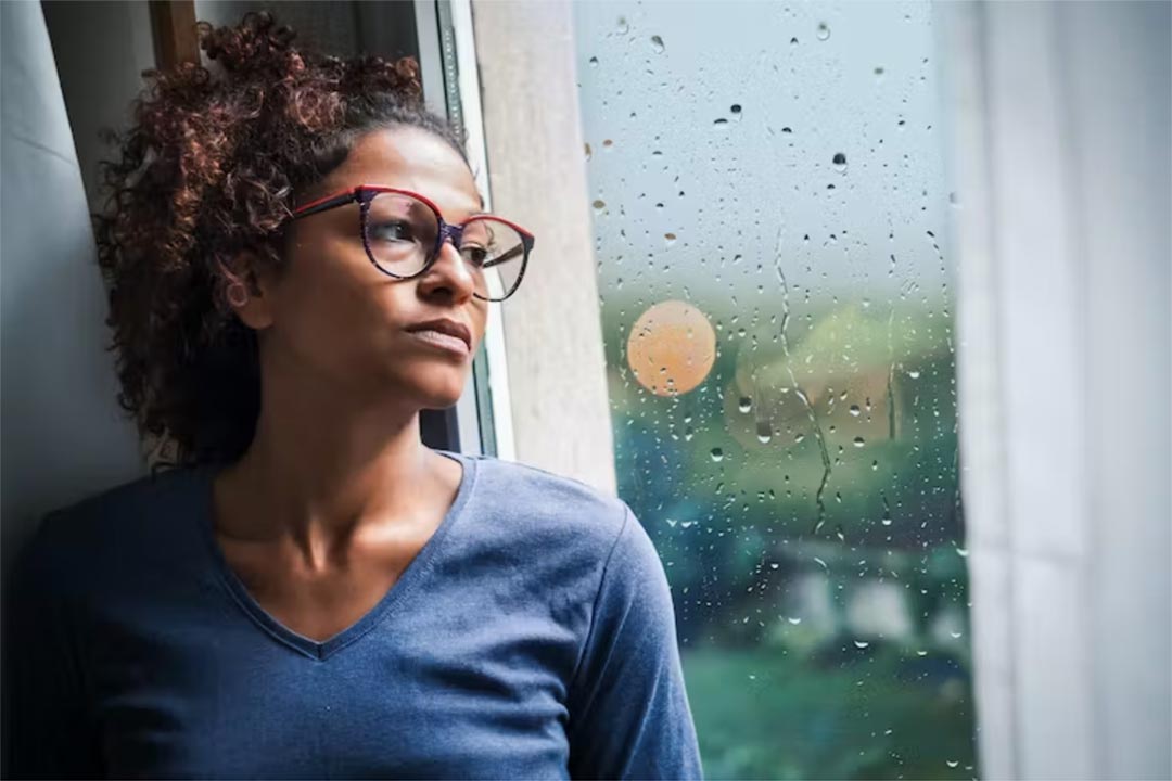 Woman looking out a window. Credit: tommaso79/Shutterstock