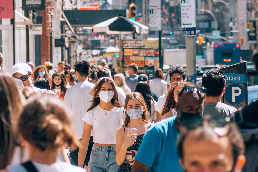 Masked people on a busy street. Credit: Yoav Aziz on Unsplash