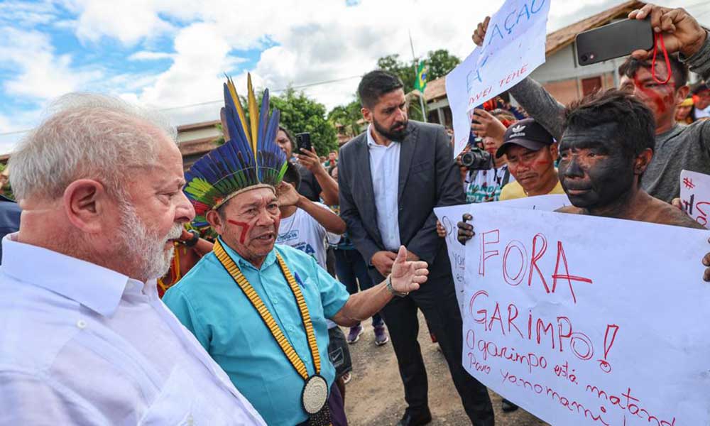 A Yanomami person holds a sign saying “Get Out Miners. Mining is killing the Yanomami people” during President Luiz Inácio Lula da Silva’s recent visit to Roraima amid the Indigenous humanitarian crisis. Image © Ricardo Stuckert/Palácio do Planalto/Agência Brasil.