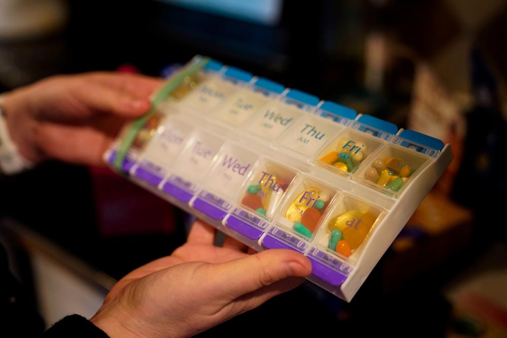 In her Fairfax, Virginia home in 2022, Eve Efron, who at the time had been struggling with long Covid for nearly a year, goes through the pills and supplements she takes to help manage her symptoms. Martha Eckey’s surveys asked long Covid patients detailed questions about medications and supplement they used, and their perceived affects. Now, that data may be bearing fruit. Visual: Carolyn Van Houten/The Washington Post via Getty Images