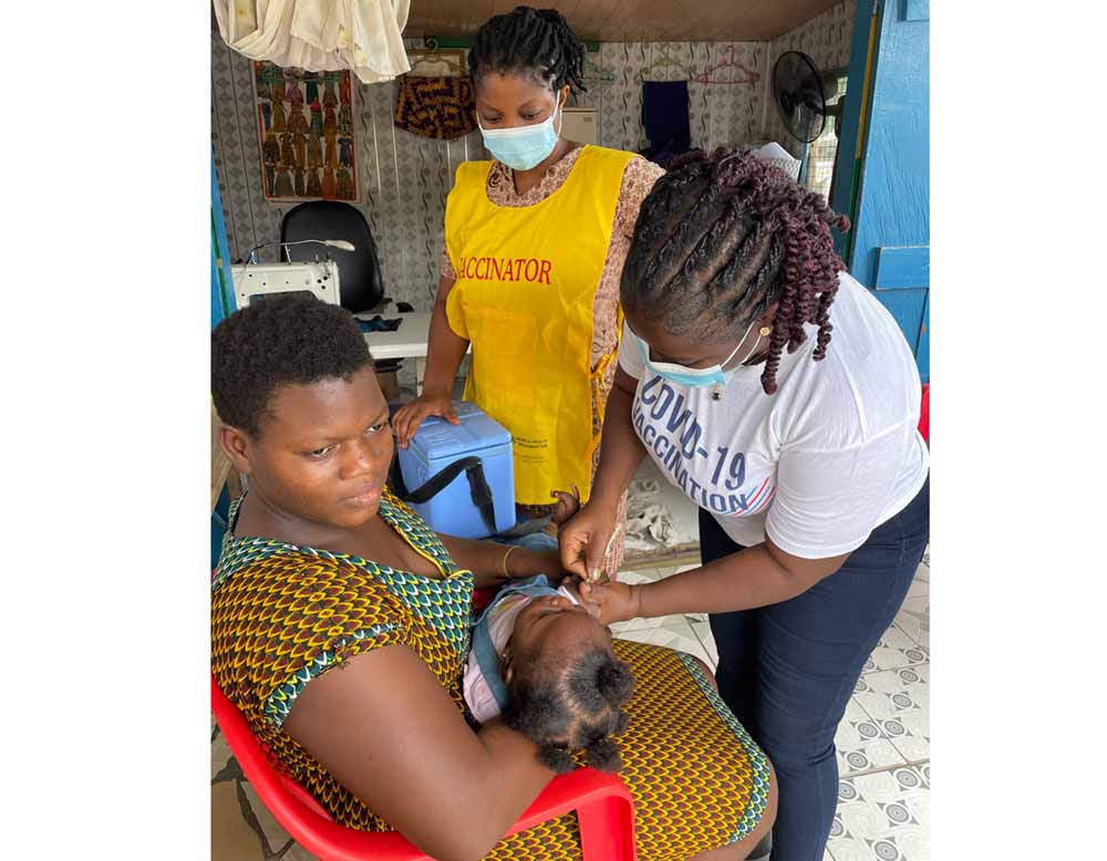 Tailor Mary holding her daughter, Yvonne, as she receives her yellow fever vaccine. Credit: Nanama Boatemaa Acheampong
