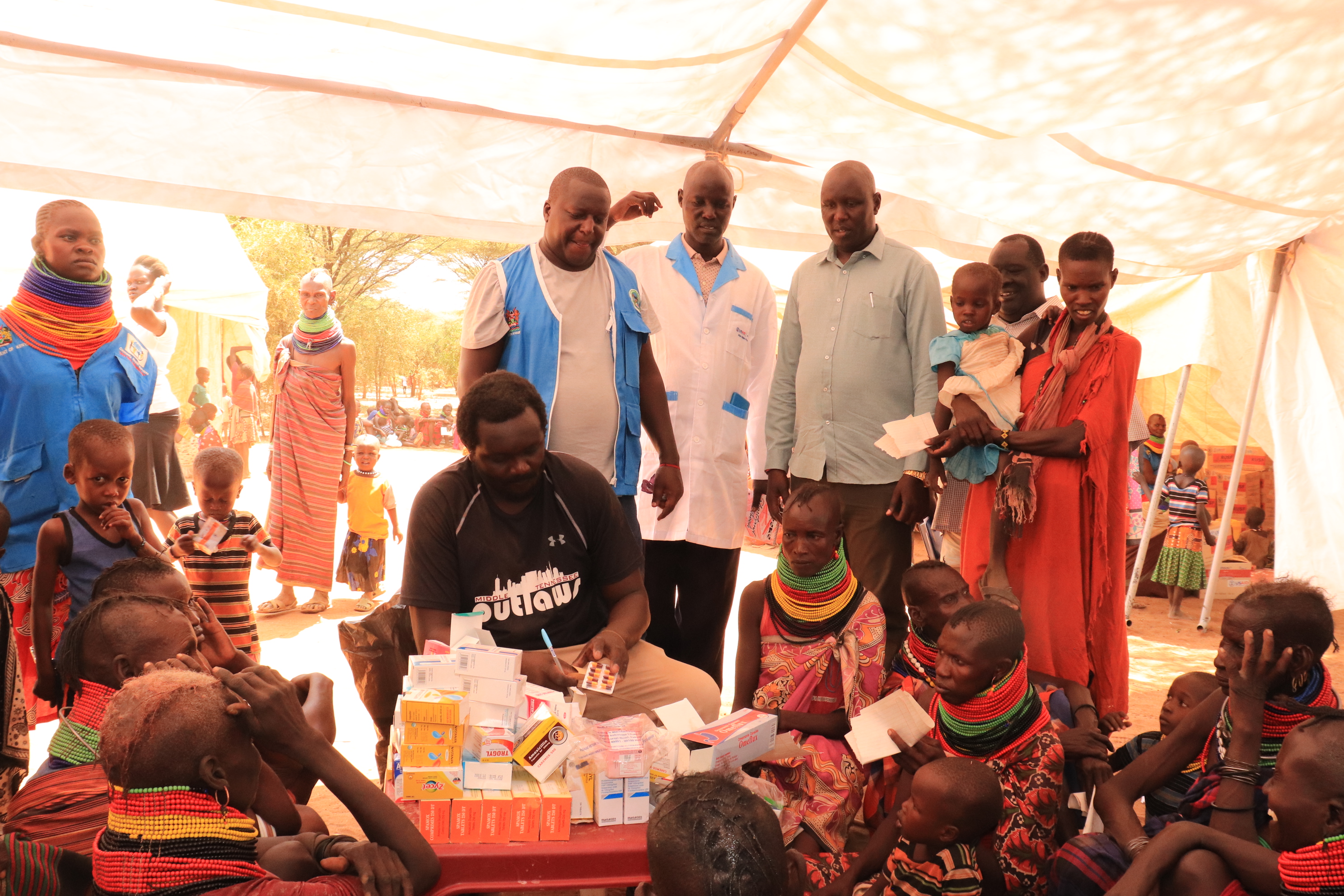 Turkana County Chief Officer Preventive and promotive health Peter Lomorukai (checked green shirt ) and the County One health coordinator Robert Rotich (in blue half court) observes a postnatal clinic during a Kimormor outreach in Turkana County held on June 13th to 22nd. Credit: County government of Turkana