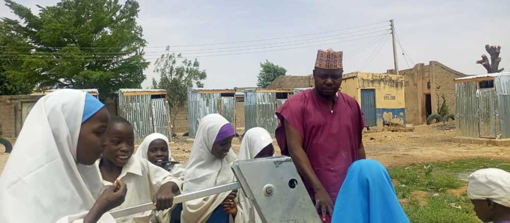 Musa Bako, community leader and assistant head teacher at Bello Bayi Primary School in Hadejia, Jigawa together with some pupils. Credit: Afeez Bolaji