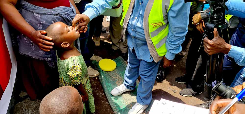 A young girl is getting vaccinated against cholera by the DRC minister of humanitarian affairs in kanyaruchinya idps camp during a mass vaccination campaign with WHO support in North Kivu. Photo: WHO / Eugene Kabambi