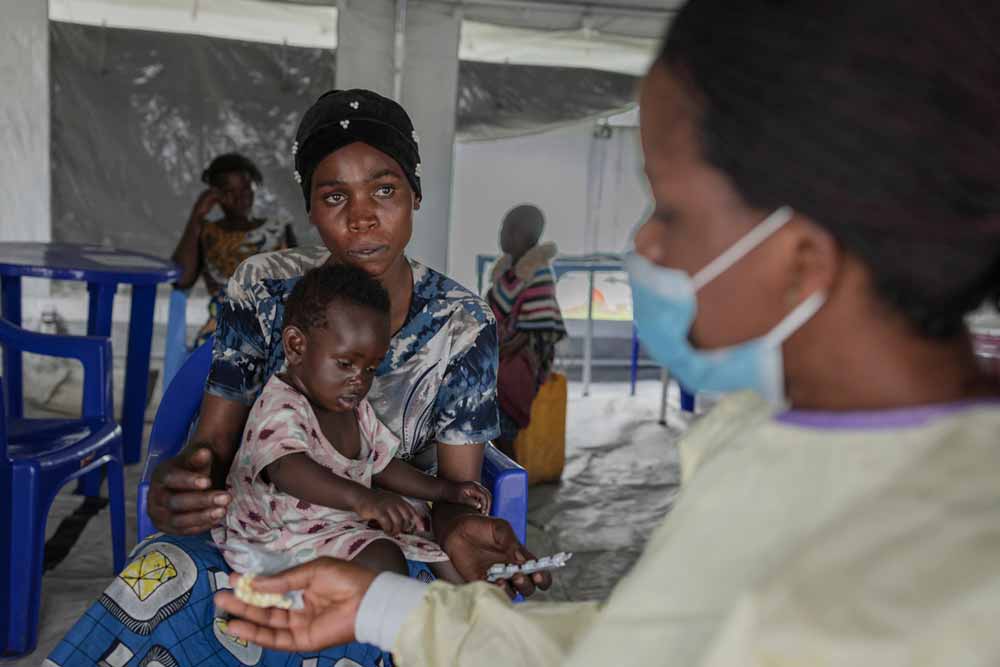 "I was sick, but now I feel well. Having this health center here in the camp helps us a lot. My child is sick. After this visit I hope she will be fine. She has diarrhea due to the poor living conditions." — Rebecca, 37, receiving medicine for her one-and-a-half-year-old daughter at the transit health center set up by WHO and partners at Bulengo camp. "I've been here for two weeks. Life is very complicated. We can't keep the children healthy because they don't eat well." Photo: WHO / Guerchom Ndebo