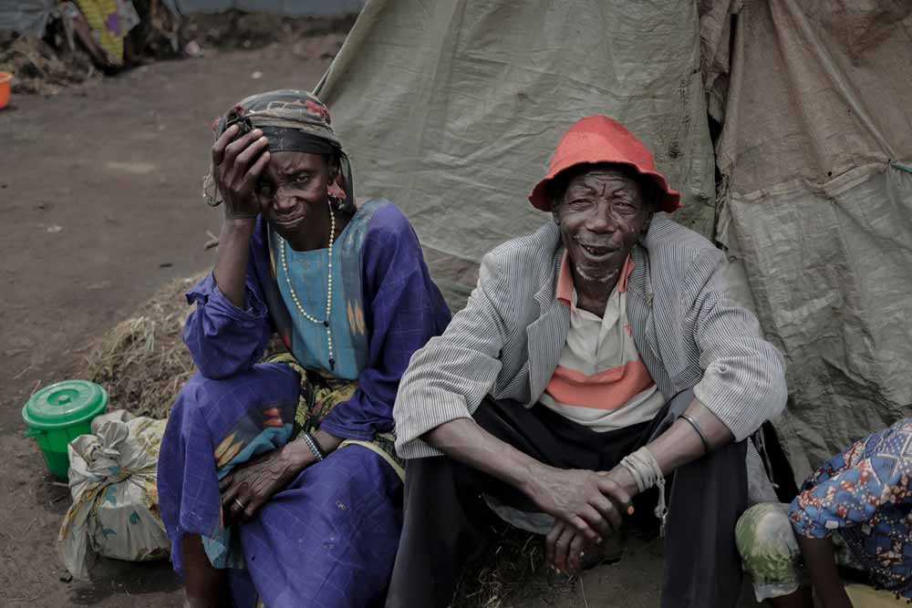 Jean-Marie, 71, sits with his family in front of their shelter; they fled their home to Bulengo camp in February.  He worries that the camp situations are worsening.  “Things don’t change. People want to get back to where they came from. Their village. Their town.” Photo: WHO / Guerchom Ndebo