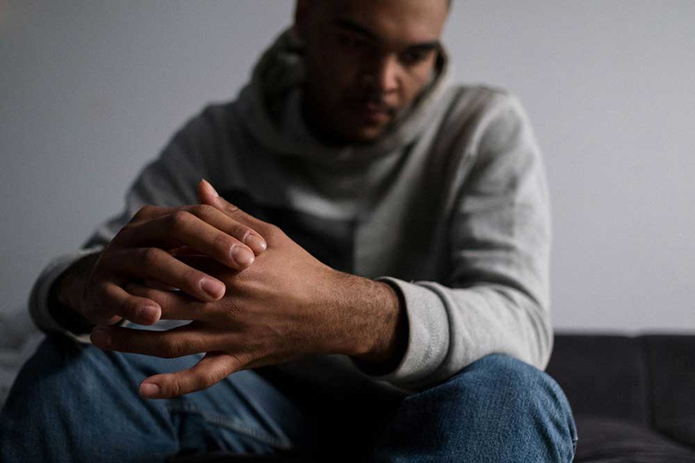 Man with his face in the shadows, hands in foreground,