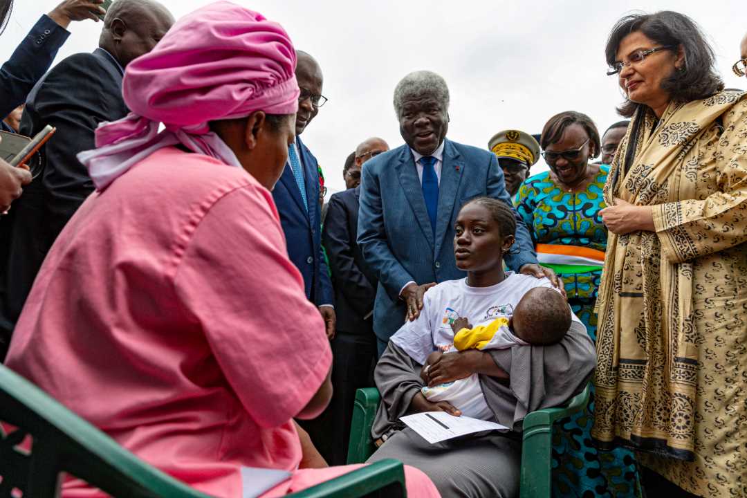 Aïcha Kouyaté holds her son Aboulaye, who received the first dose of the R21 vaccine as Côte d'Ivoire began routine malaria vaccinations. Prime Minister Robert Reugré Mambé, Health Minister Pierre Dimba and Gavi Chief Executive Officer Sania Nishtar attended the event. Credit: Gavi/Miléquêm Diarassouba