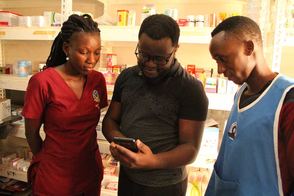 Andrew Ddembe The Founder Of MobiKlinic shows health center workers how the MobiKlinic App works.