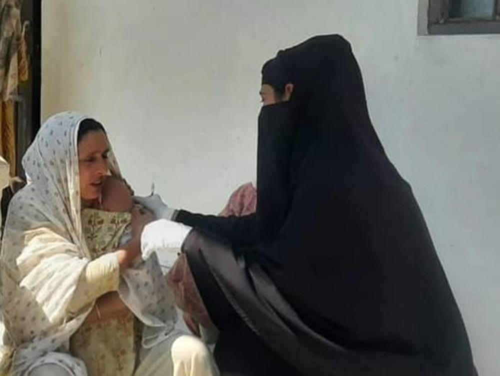 Bilquis Ara vaccinating an old lady in a remote village of Langate in Kashmir. ASHA workers played an important role during COVID-19 vaccination drive in the country.. Credit: Nasir Yousufi)