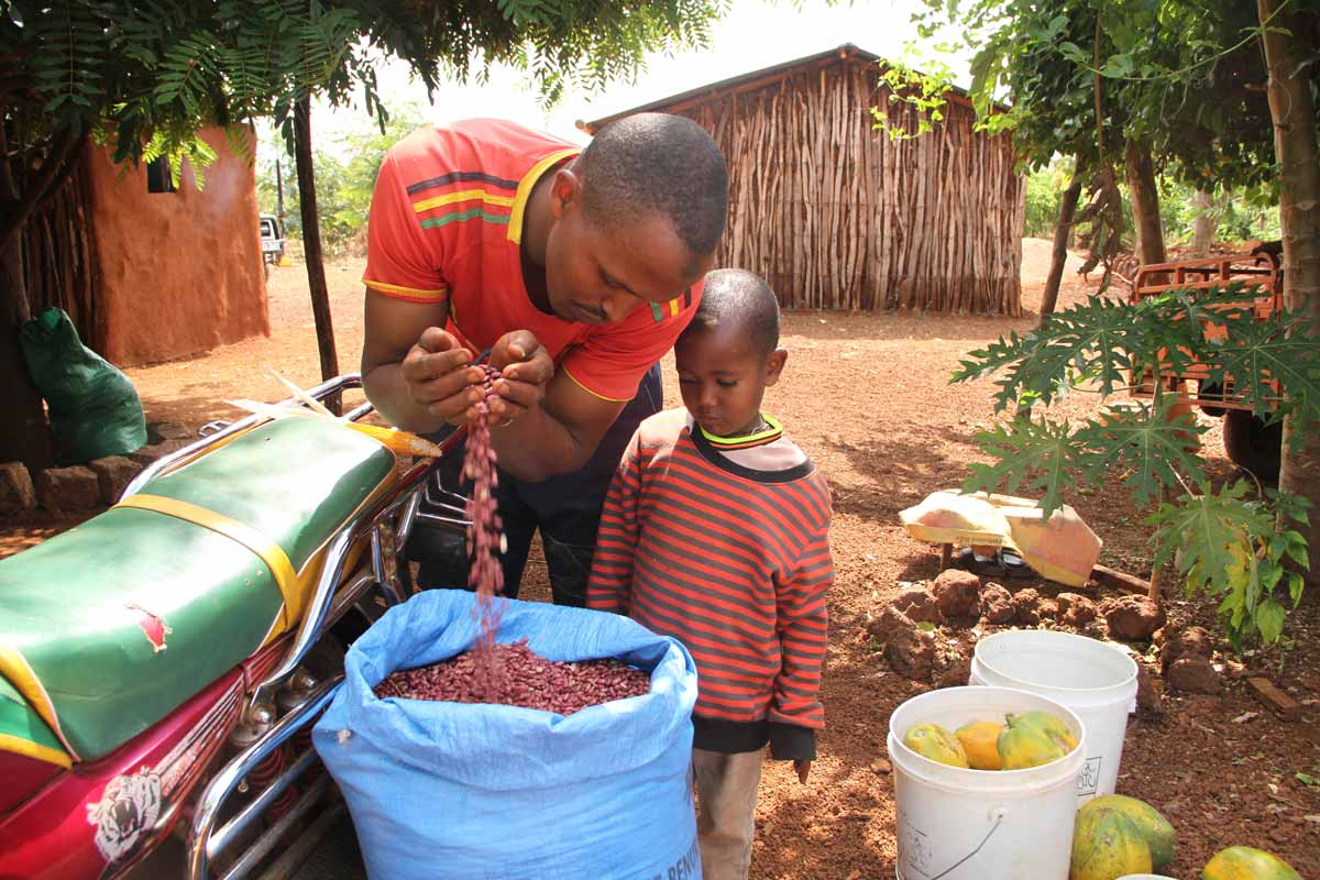 Abdub Jarso and his son with beans, pawpaws and honey from his farm. Credit: James Karuga