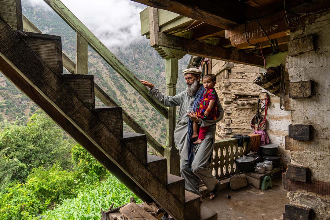 Roqia’s grandfather carries her up one of the steep wooden staircases that connect the different levels of their mountainside village in Afghanistan. She has regained the ability to walk since contracting polio last winter, but she still spares her left leg. © UNICEF