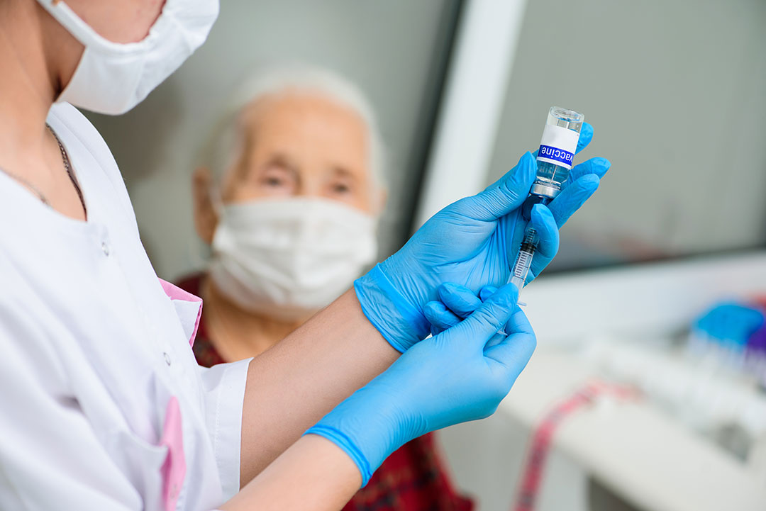 A nurse prepares to vaccinate an elderly woman.