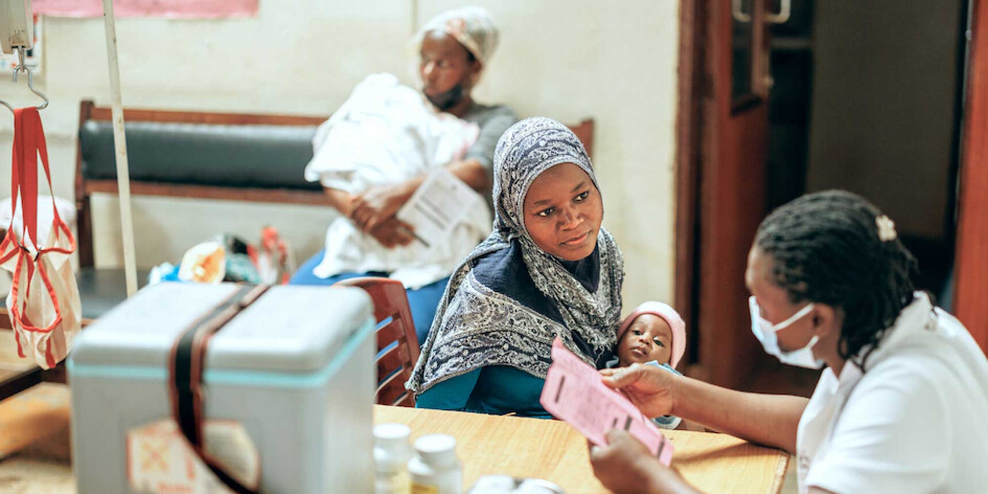 A mother with her baby talking to a nurse at a health clinic in Kampala, Uganda. Credit: Gavi/2024/Jjumba Martin