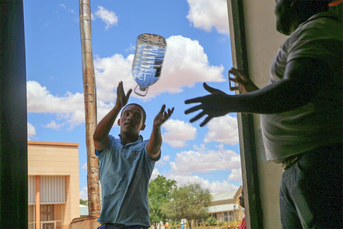 A community member helps to offload donated water in the small town of Kenhardt, South Africa, in 2020. While charity can greatly benefit people during extreme weather events, long-term government support is needed to weather the long-term physical and mental stressors of ongoing global warming. Image by Petro Kotze.