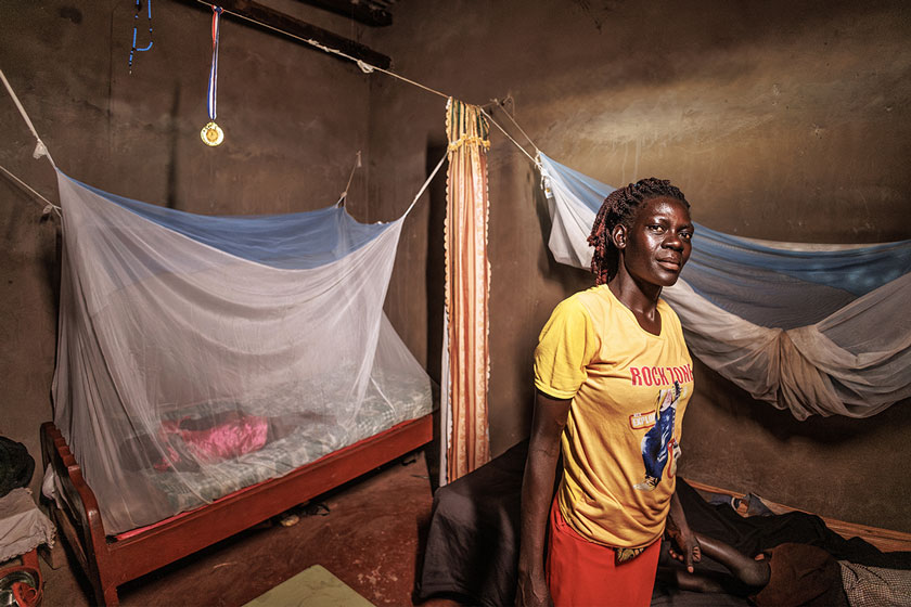 Mother-of-four Aguti Nancy tucks her children in under a treated bed-net to put a physical barrier between them and the malaria-carrying mosquitoes.