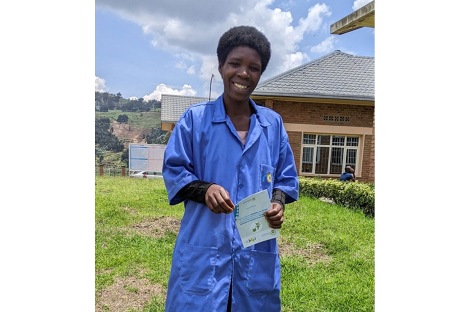 A happy community health worker poses for a picture holding a brochure entailing health information. Credit: Germain Nsanzimana