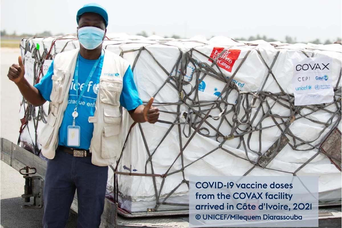 Man at airport next to a large crate containing boxes of vaccines