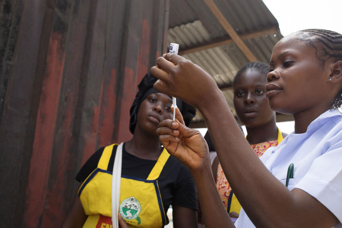Itu vaccinates a little girl against Malaria. Outreach for vaccination against malaria in children under five months. The team, led by Itu, vaccinator, (white blouse), goes door to door in the city center to ask parents if their children have received the vaccine against malaria. Onuegbu community, Ogbia, Nigeria. December 18, 2024. Credit: Jérôme Sessini