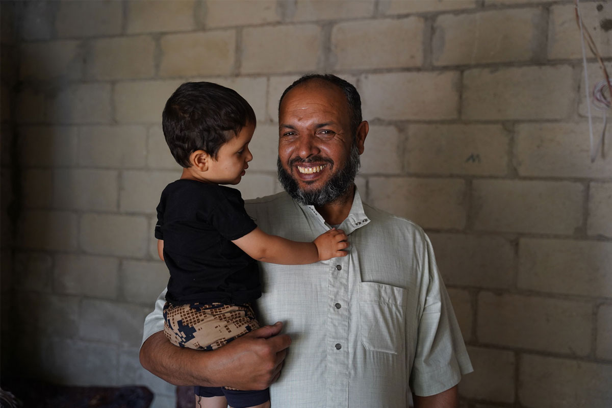 Jameel, displaced from Homs and now living in Idlib, holds his son after ensuring all his children received their vaccines. Credit: WHO
