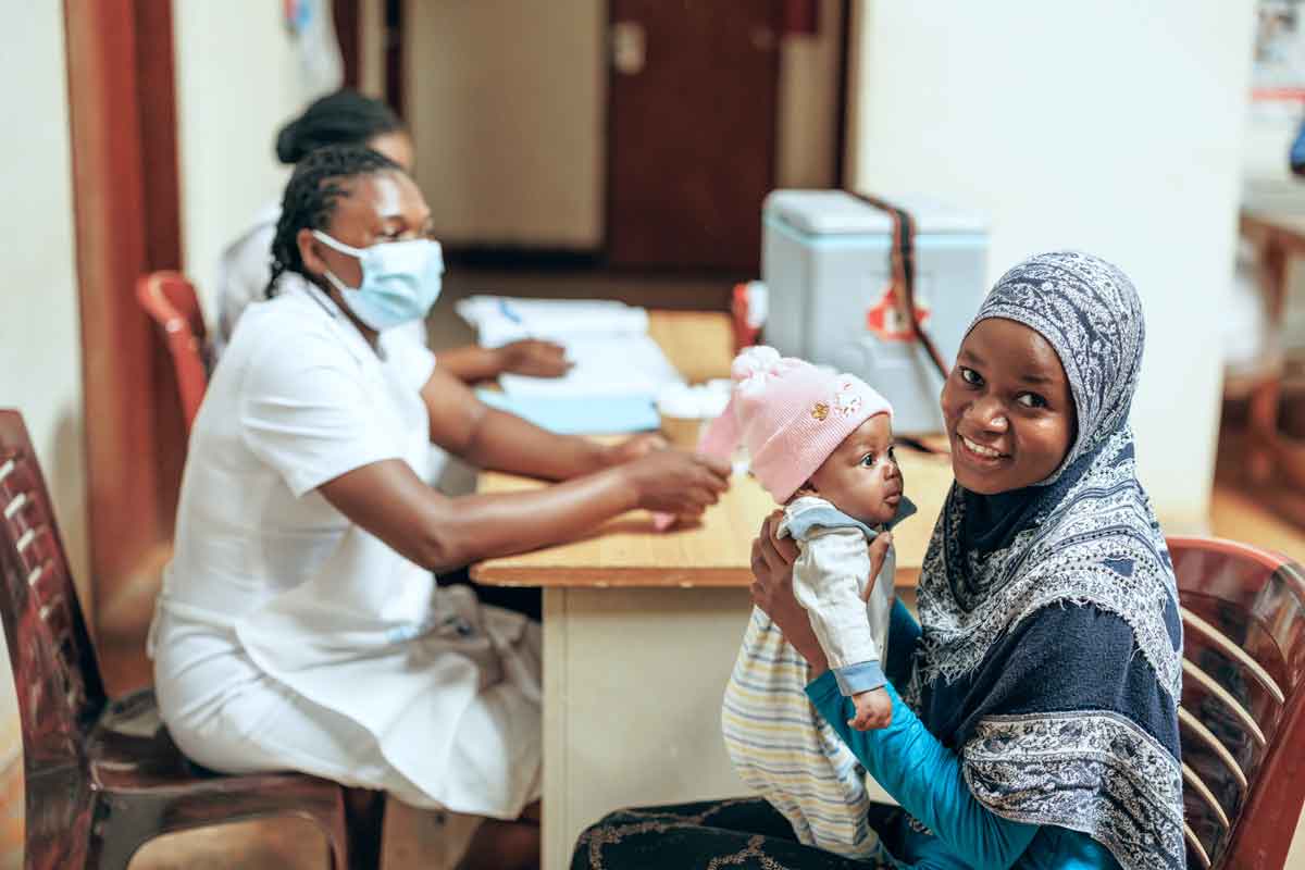 A mother with her baby talking to a nurse at a health clinic in Kampala, Uganda. Credit: Gavi/2024/Jjumba Martin