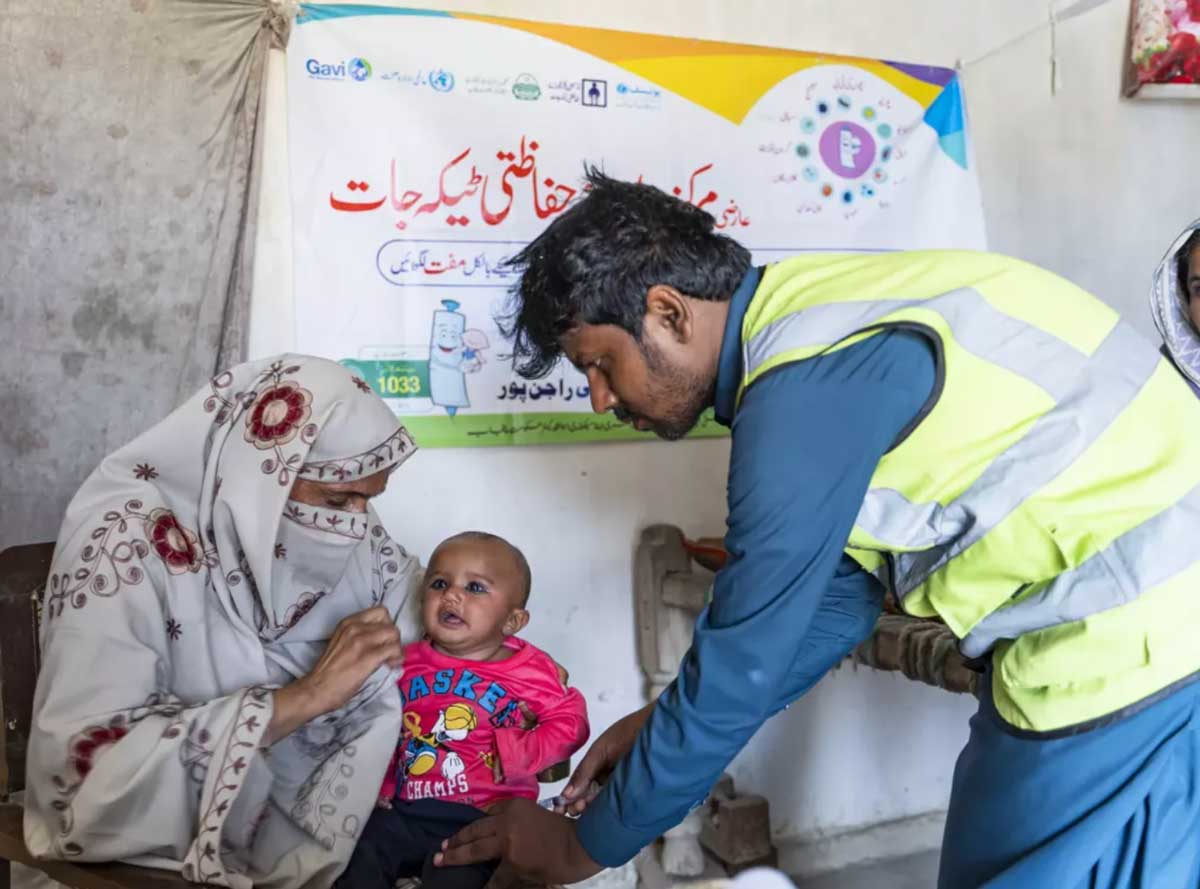 Vaccinator Adnan Haider (Right) is immunizing Husna (4 months) held by her mother Nasreen (Left), in a vaccination outreach Kit Station in the flood-affected village Basti Sahu, Rajanpur district, Punjab. UNICEF/Pakistan/Owais M. Rafiq