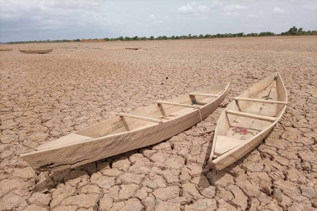 Wooden boats stranded on a cracked, dried-out lakebed during severe drought. Credit: Yoda Adaman/Unsplash