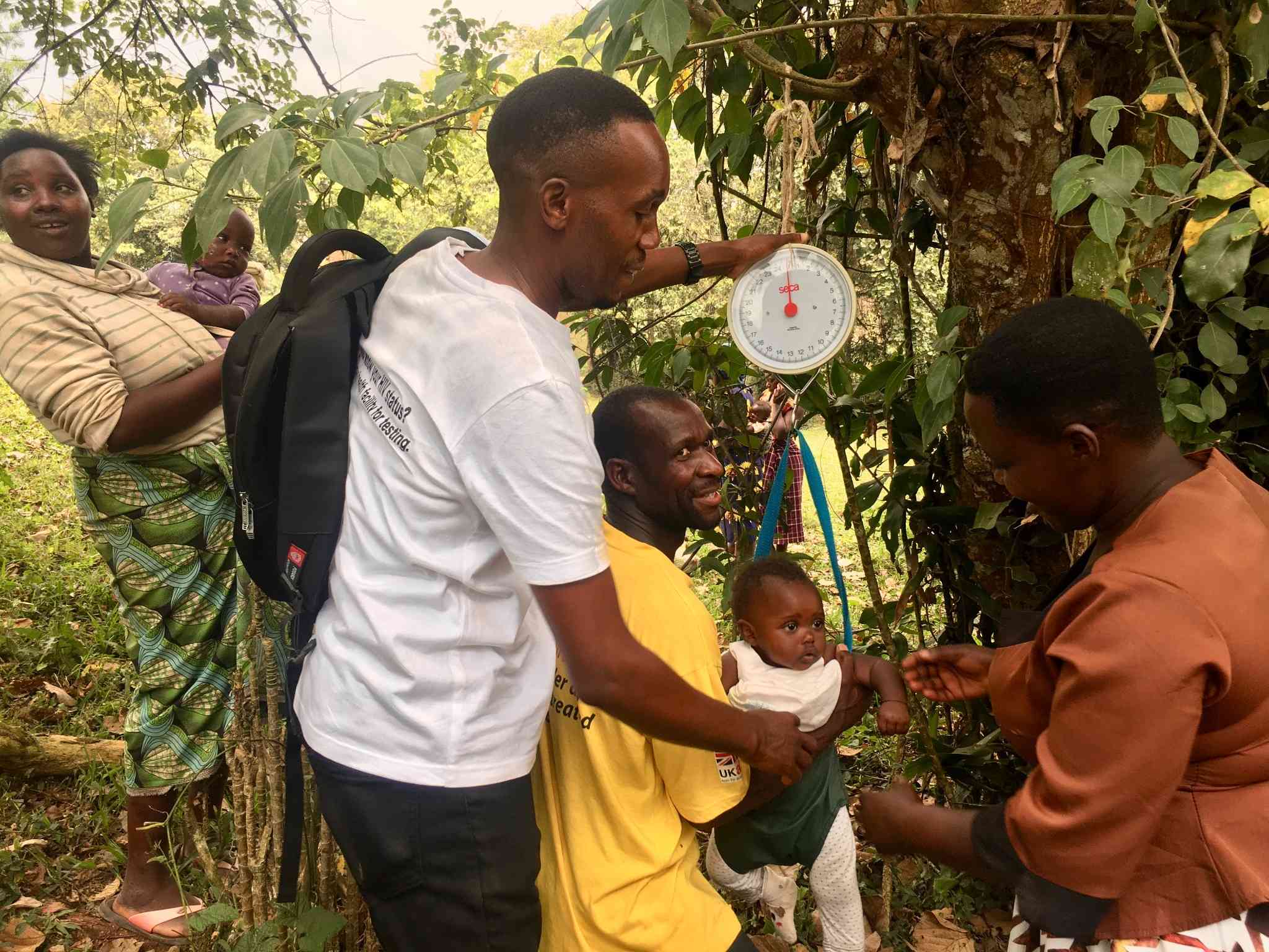 A community health worker from InPact-Uganda (in white) helping to take a baby's weight in Kajugangoma village in Kanungu.. Credit_John Agaba